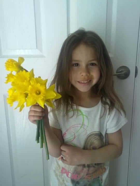 Girl smiling while holding yellow daffodiles